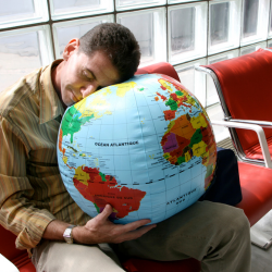 image of aman asleep on a blow up globe