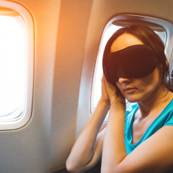 image of a woman asleep in a face mask on a plane
